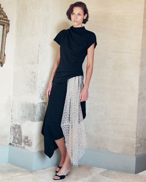 A woman wearing a black dress with a sheer lace skirt.