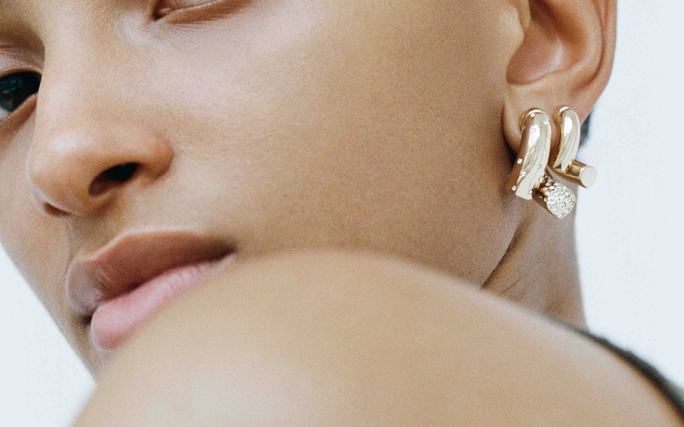 A woman wearing gold and diamond Tabayer earrings.