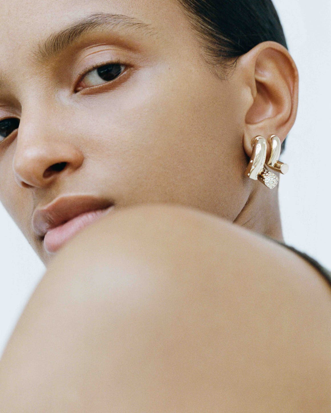 A woman wearing gold and diamond Tabayer earrings.
