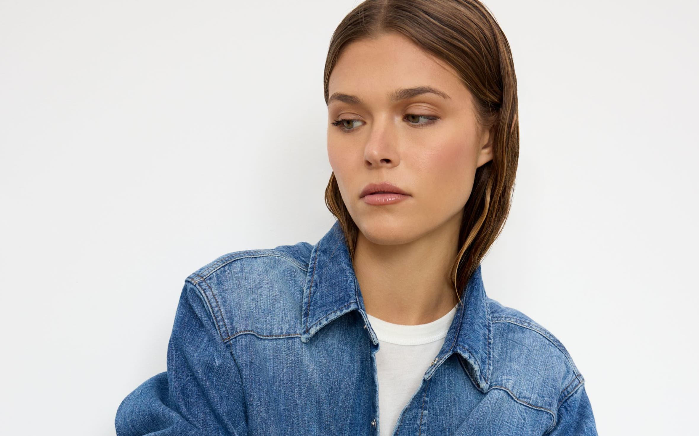 A woman wearing a denim button-up shirt and matching jeans.