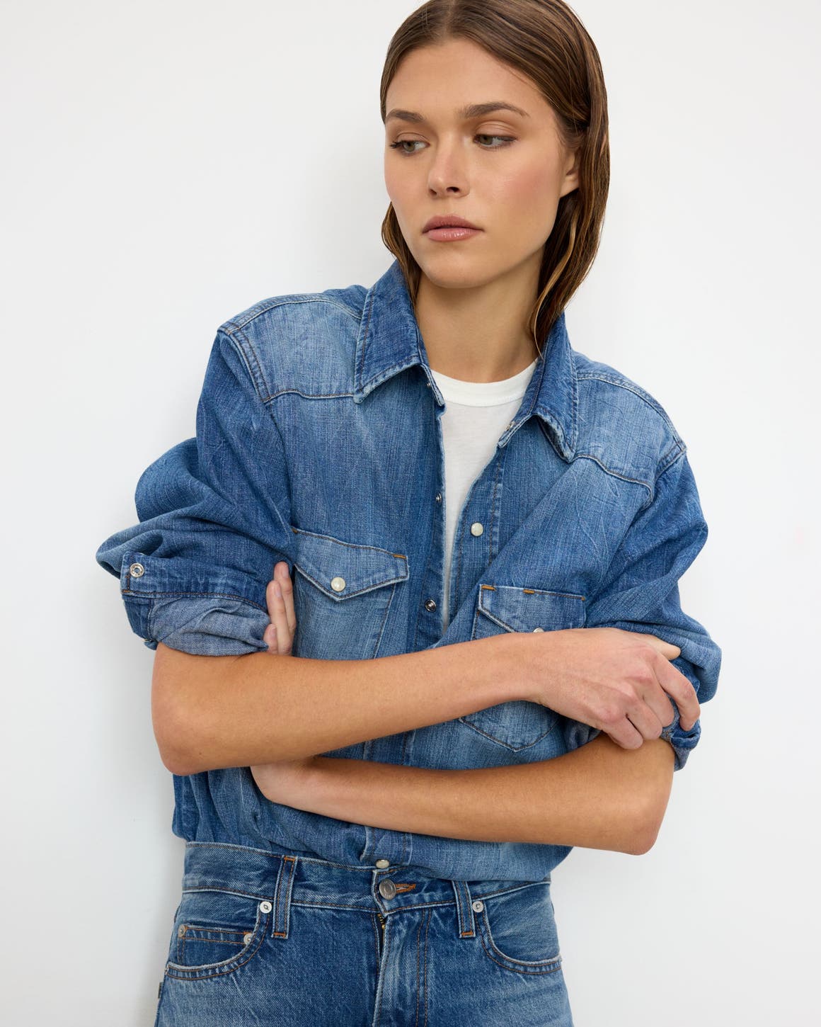A woman wearing a denim button-up shirt and matching jeans.
