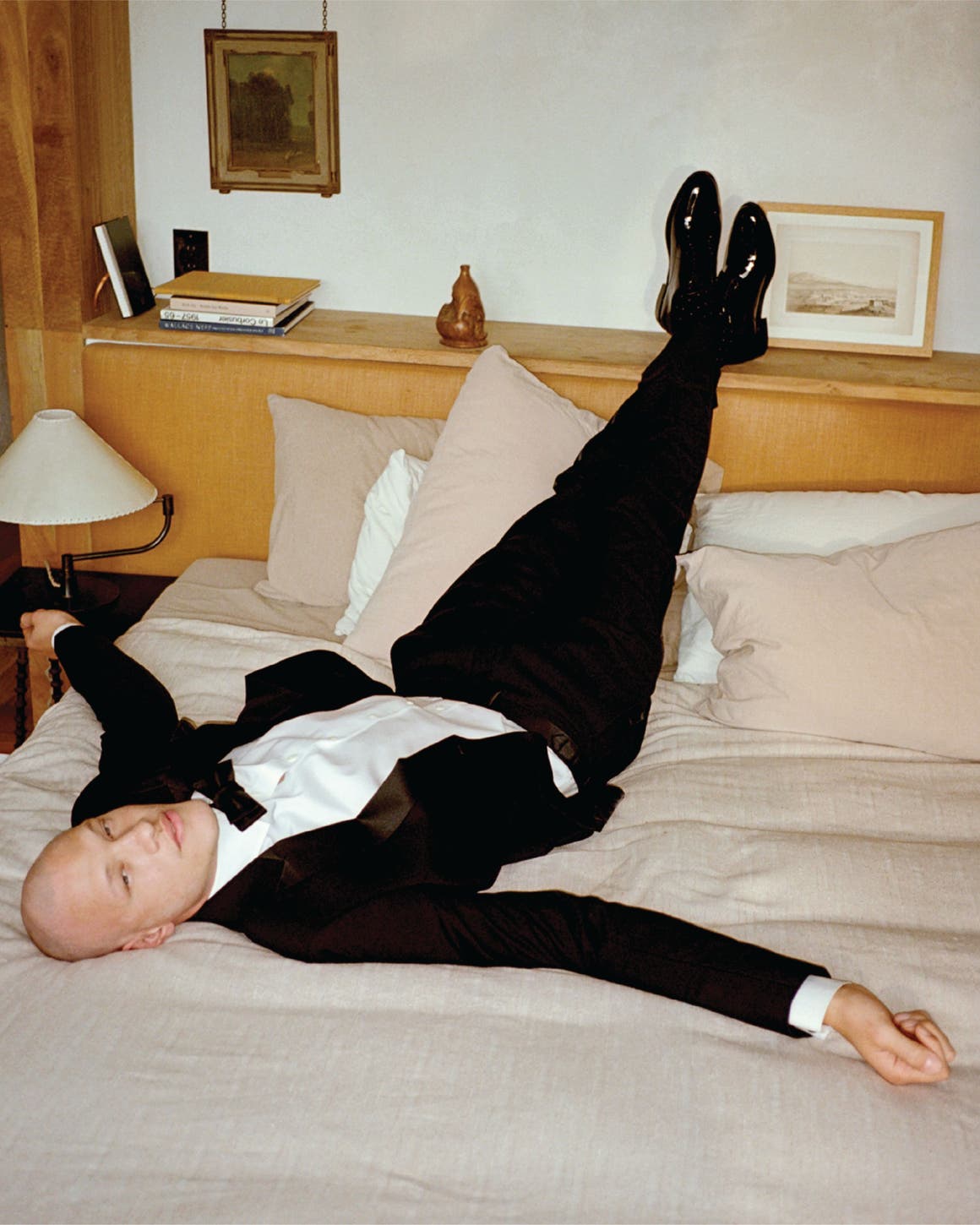 Man on a bed wearing a tuxedo.
