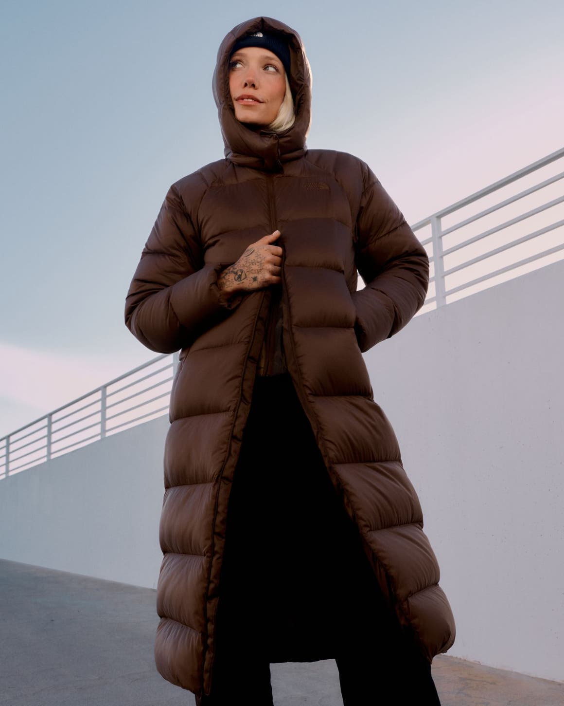 A woman in a long brown hooded North Face puffer coat.