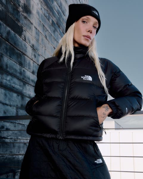 A woman wearing a black North Face puffer jacket and beanie.