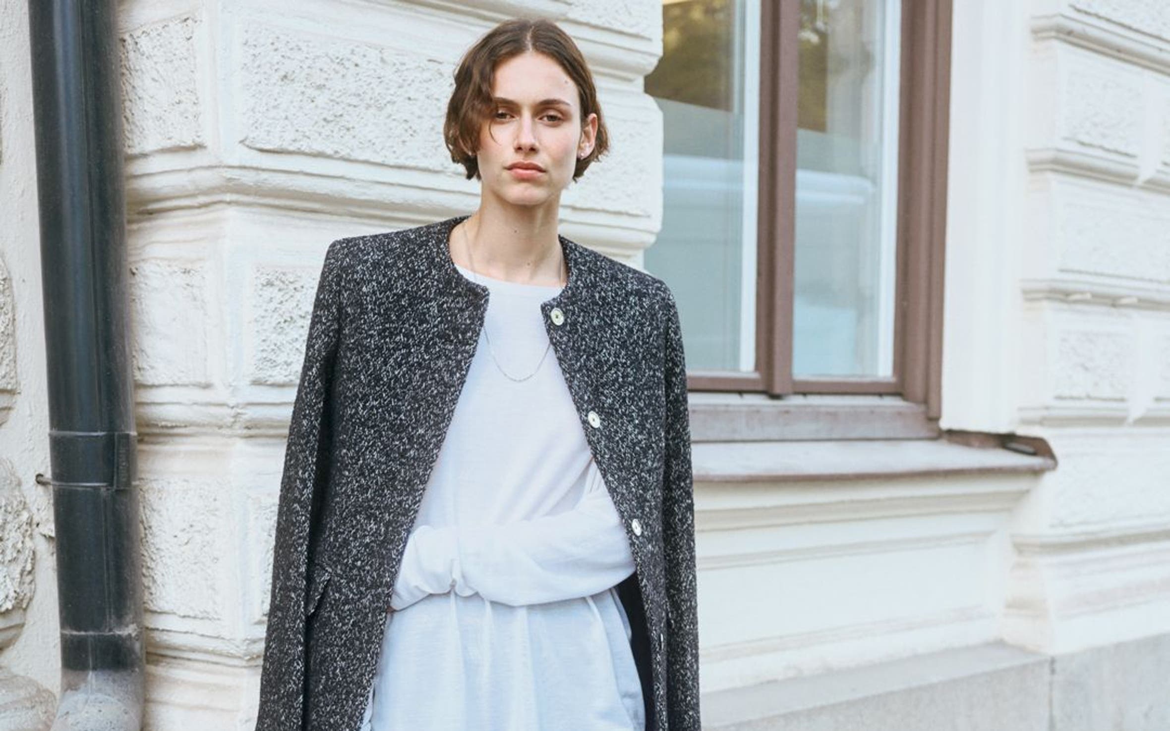 Woman wearing a jacket, top, pants, handbag and shoes from TOTEME.