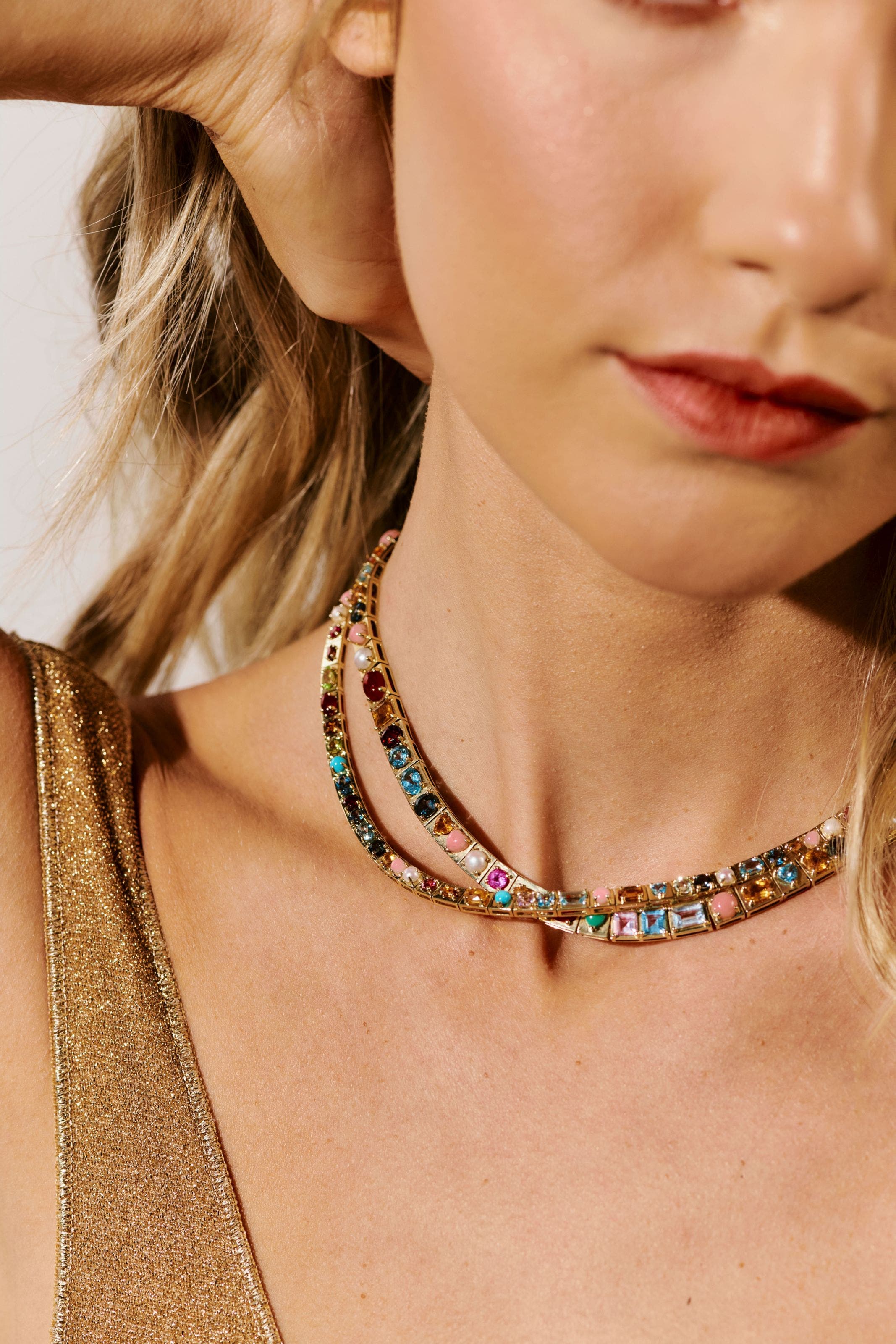 A woman wearing gem-encrusted gold necklaces. 
