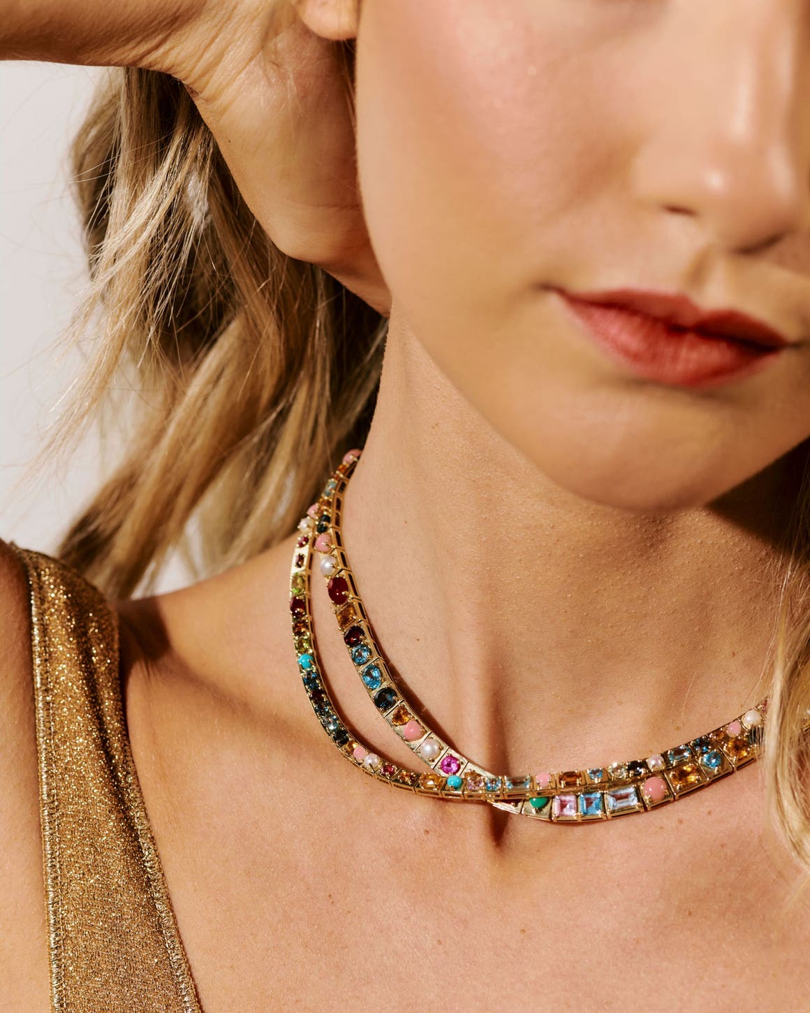 A woman wearing gem-encrusted gold necklaces.