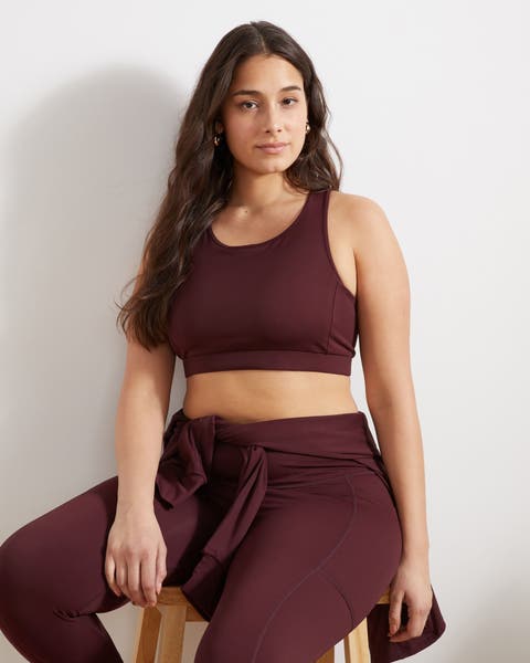 Woman in a matching plus-size sports bra and leggings with a jacket tied around her waist.