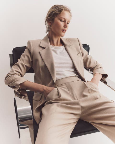 Woman wearing a beige Veronica Beard suit jacket and trousers set.