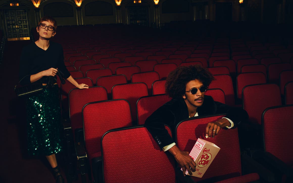 Man and woman wearing Vince looks at a movie theater.