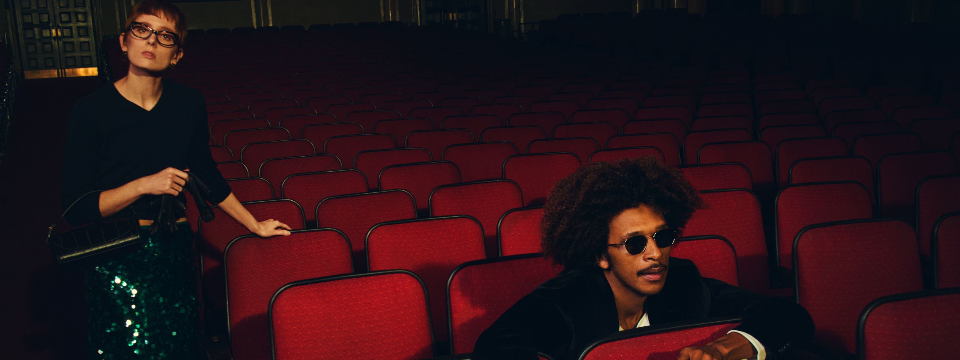 Man and woman wearing Vince looks at a movie theater.