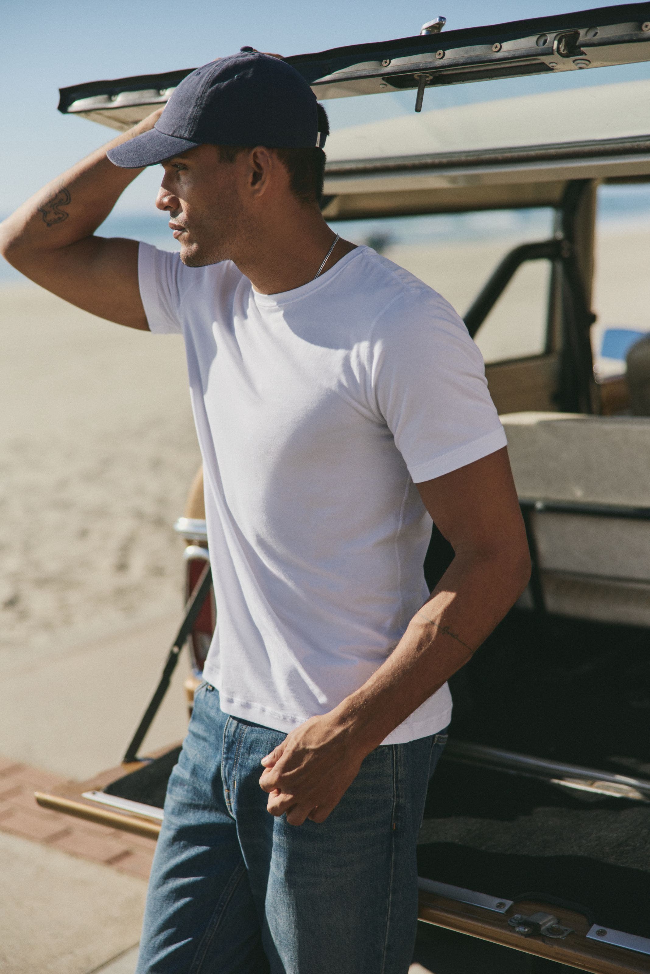 A man wearing white tee, jeans and cap. 