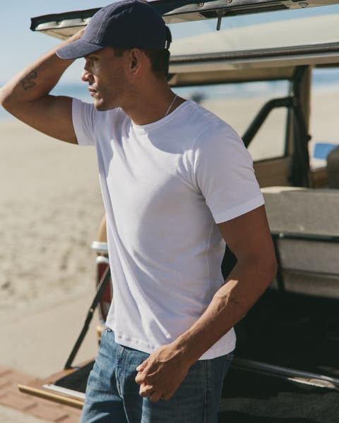A man wearing white tee, jeans and cap.