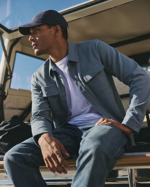 a man with a coat and hat sitting down.