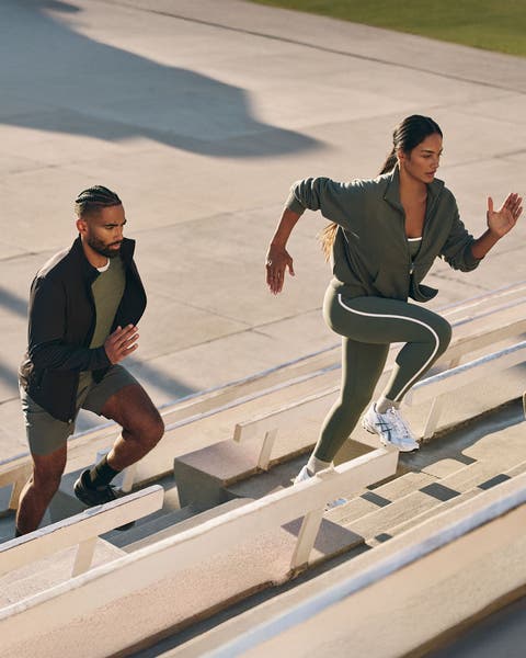 Man and woman running up bleachers wearing Vuori clothing.
