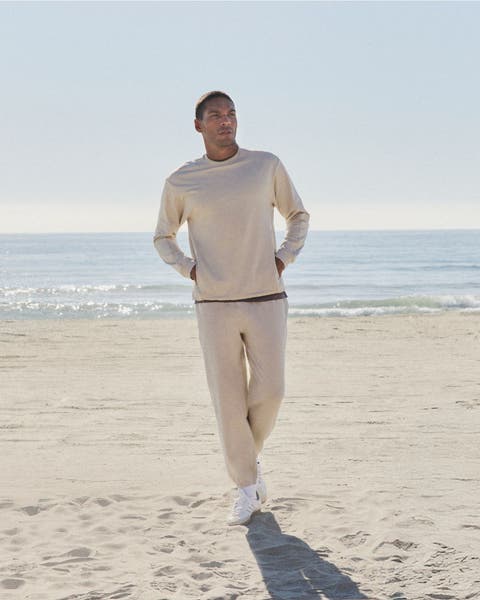 Man walking on the beach wearing Vuori clothing.