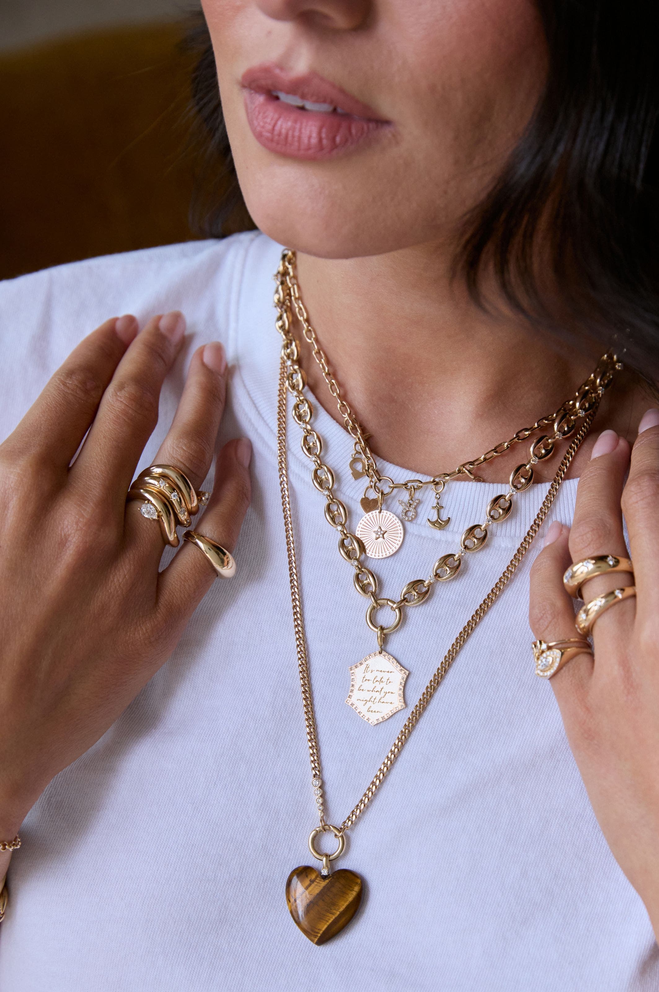 A woman wearing several gold necklaces. 