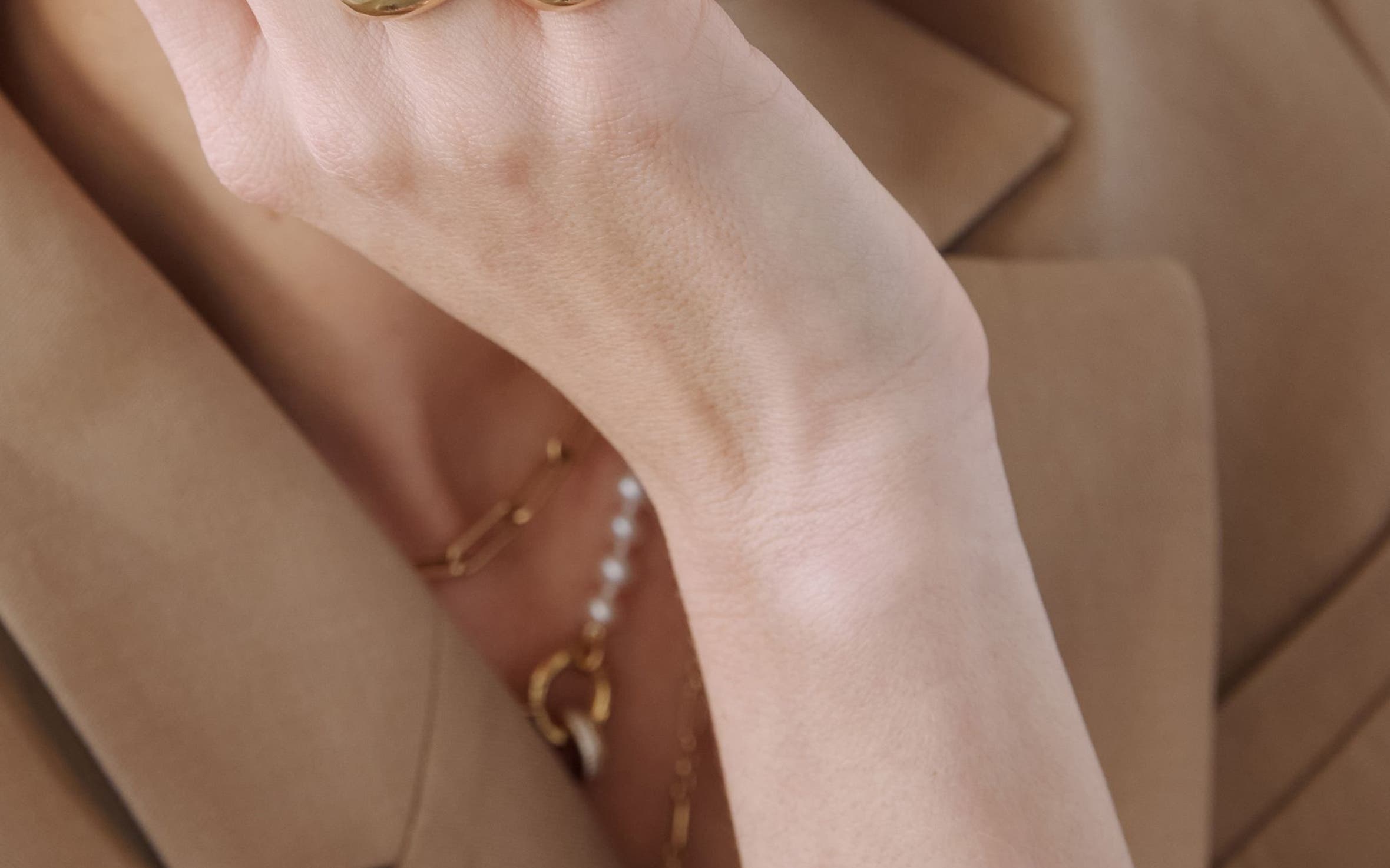 A woman wearing several gold rings, necklaces and bracelets from Zoë Chicco.