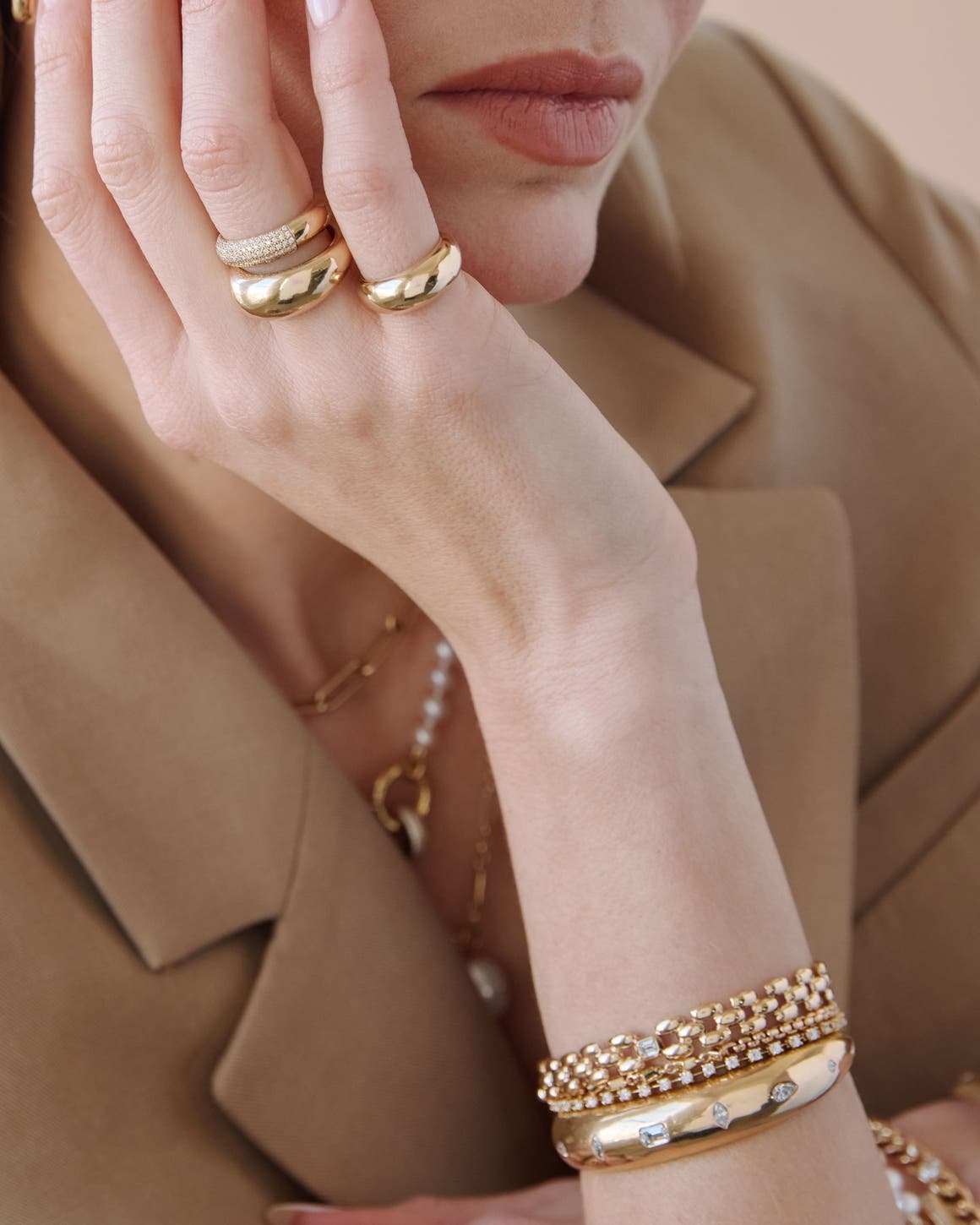 A woman wearing several gold rings, necklaces and bracelets from Zoë Chicco.