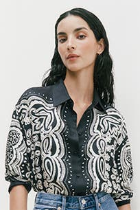 A woman wearing a button-up shirt with a paisley pattern. 