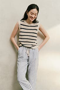 A woman wearing a striped sweater and striped pants. 