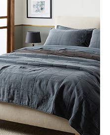 A bed made with a slate-blue comforter and pillows.