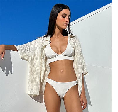 A woman in a white bikini and lace coverup.