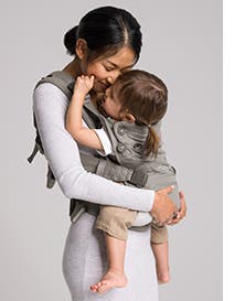 Woman holding baby in a Nuna carrier.