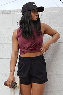 A woman wearing black active shorts with a crop top and black baseball cap. 