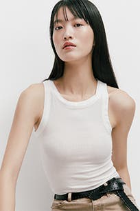 A woman wearing a white tank top. 