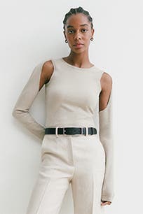 A woman wearing a beige top with cutout sleeves.
