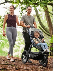 Parents pushing kid in UPPAbaby stroller on a trail.