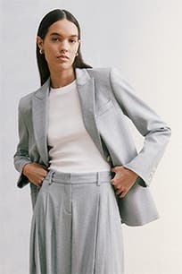 A woman wearing a grey blazer with matching trousers. 