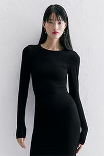 A woman wearing a long-sleeve black dress.