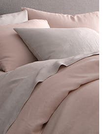 A bed made with light-pink bedding.