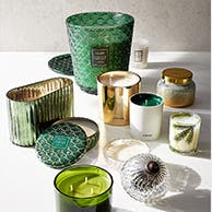 An assortment of candles in green, white and gold jars.