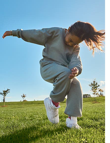 A girl playing in a sweatshirt, matching joggers and white sneakers.