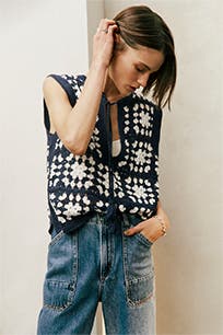 A woman wearing a crocheted sweater and jeans.  