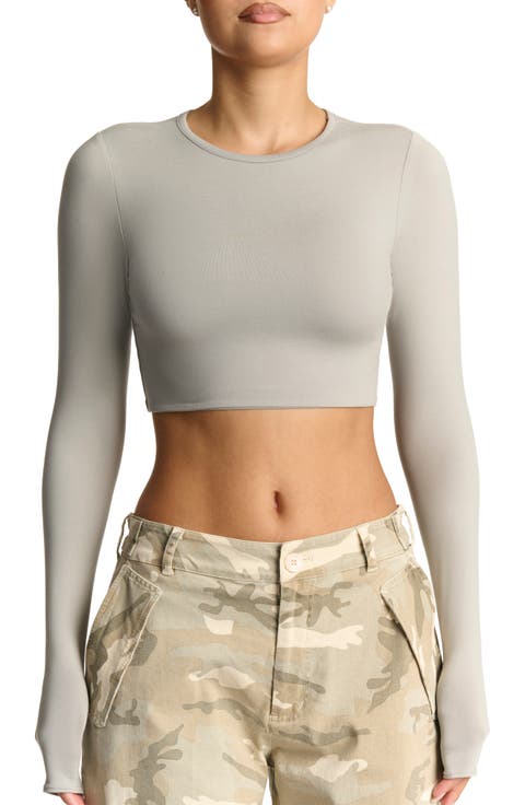 Long sleeve crop top in pastel pink with a subtle print, worn with high‑waisted jeans.