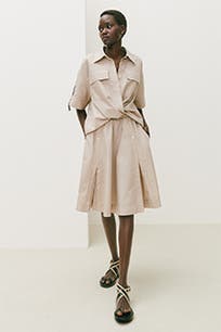A woman wearing a beige dress with a gathered waist.