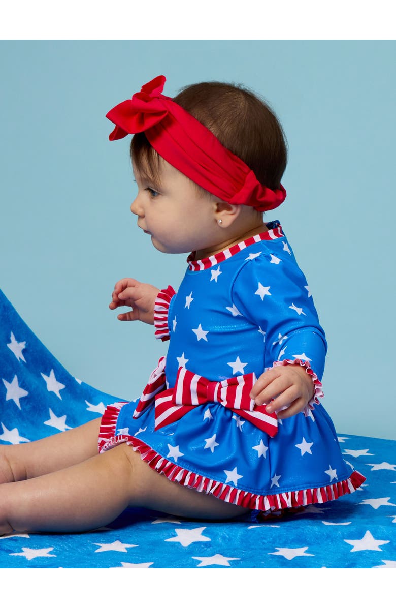 RuffleButts UPF50+ Long Sleeve One Piece Bow Peplum Rash Guard Swimsuit, Alternate, color, Shimmer Stars & Stripes